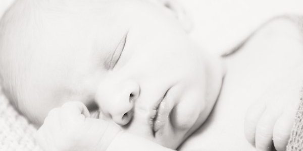 Ein Neugeborenes Baby schläft ganz friedlich im warmen Körbchen