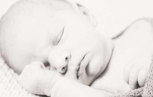 Ein Neugeborenes Baby schläft ganz friedlich im warmen Körbchen